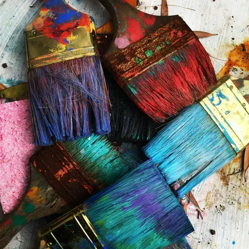Paint-covered brushes resting on a wooden surface