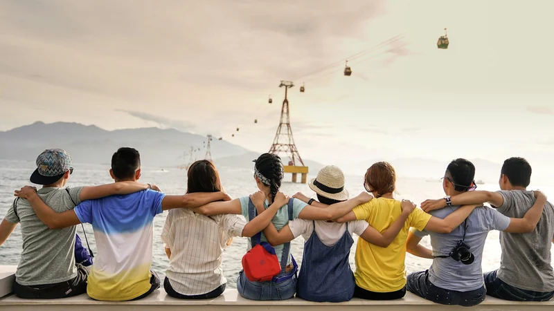 A group of people standing arm in arm watching a sunset