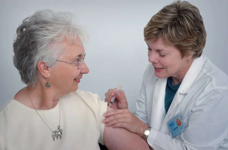 A nurse giving an older woman an injection