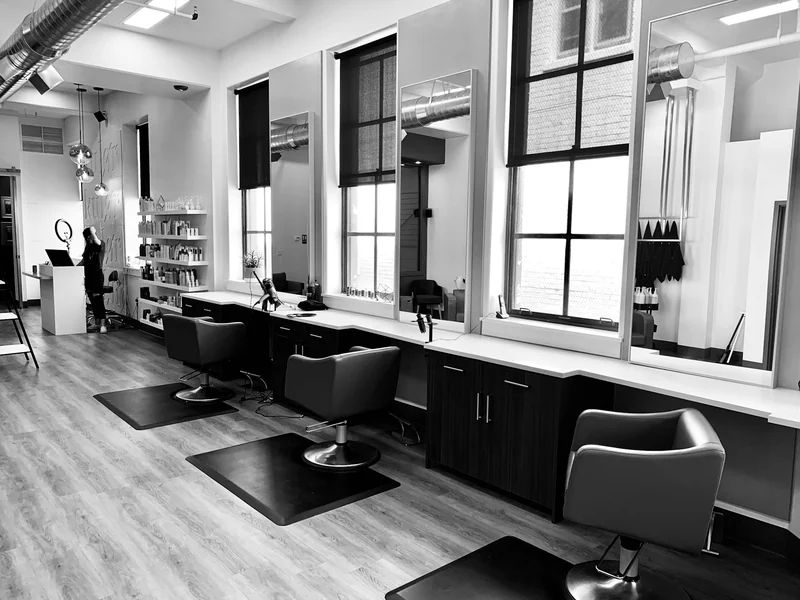 An empty hair salon with styling chairs beside the windows