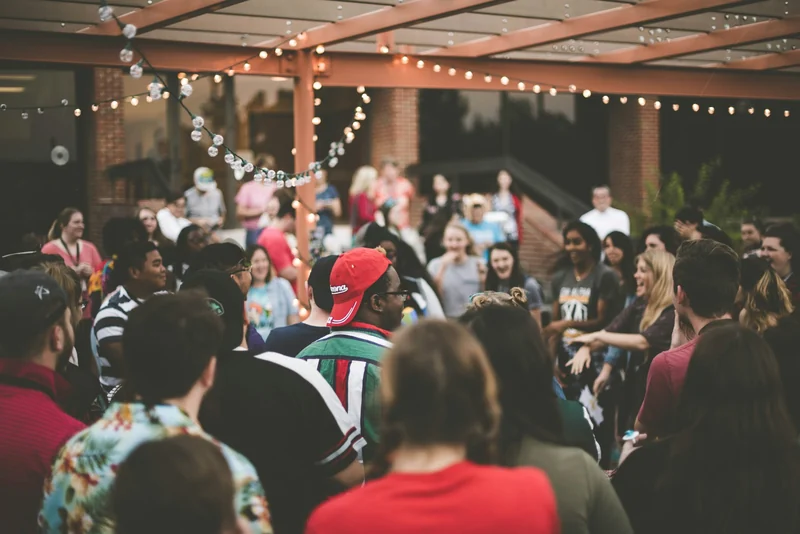 A crowd of people gathered indoors under festoon lights