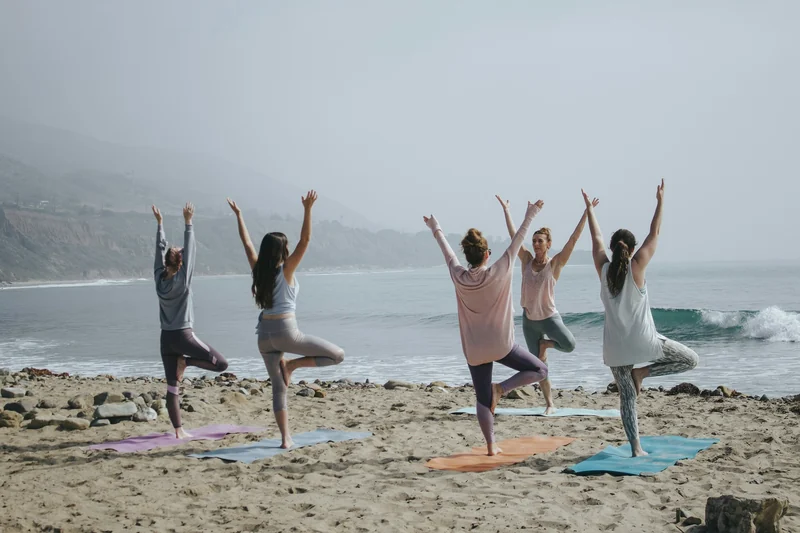 People practising yoga on a beach